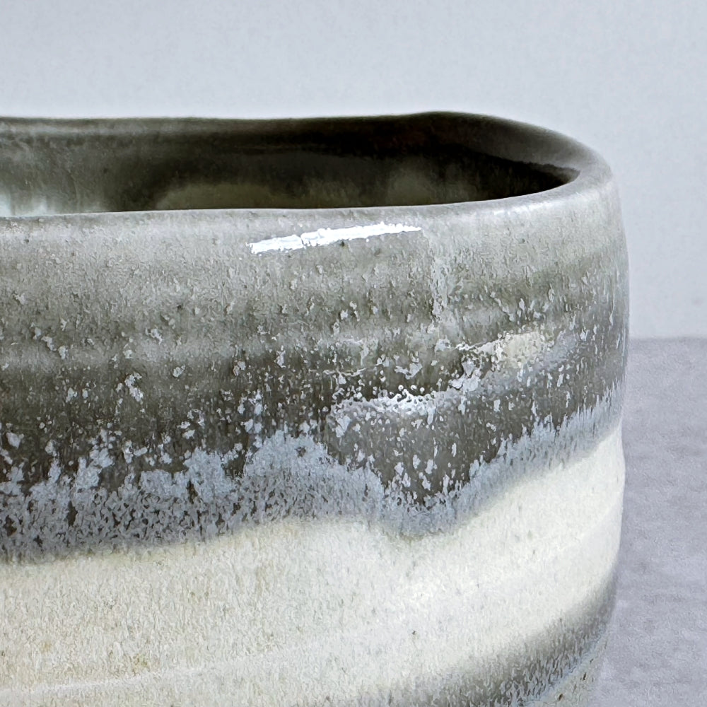 Close-up of a rim of ceramic matcha bowl with a textured surface on a light gray background