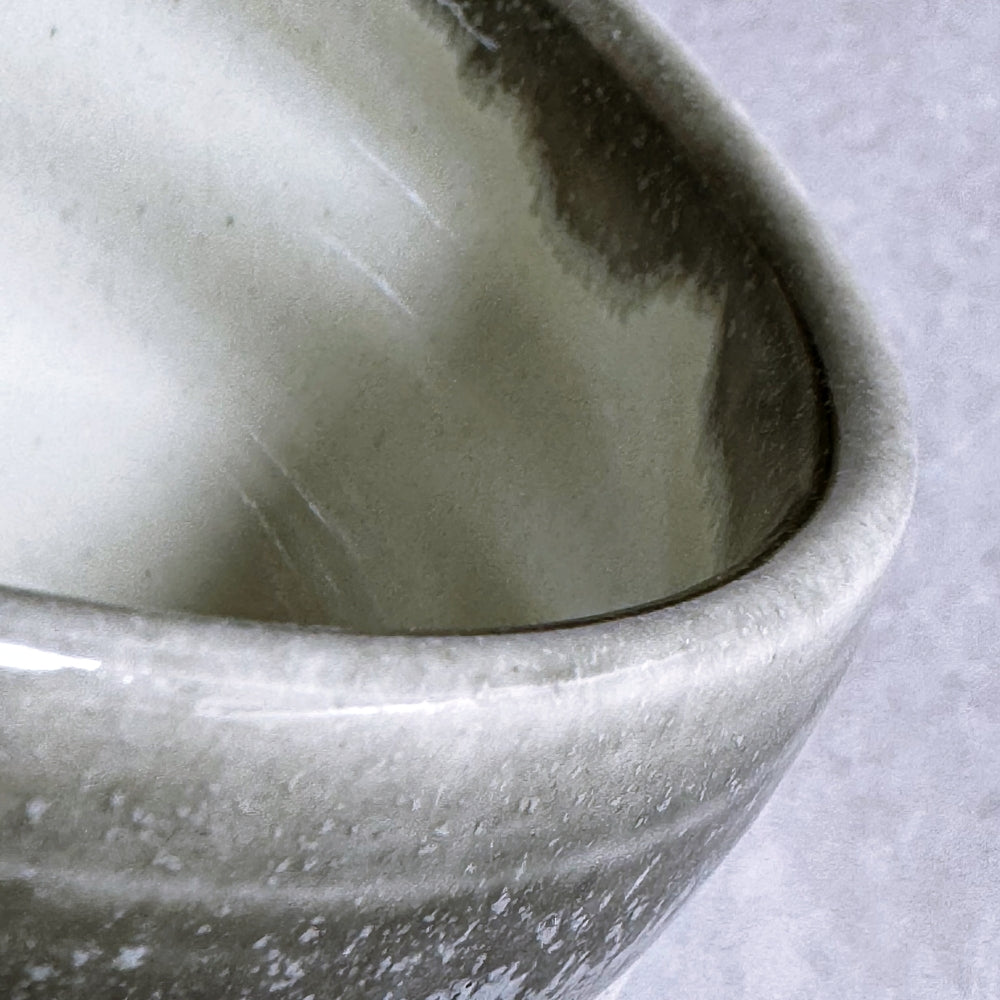 Close-up of a textured ceramic matcha bowl on a light grey background