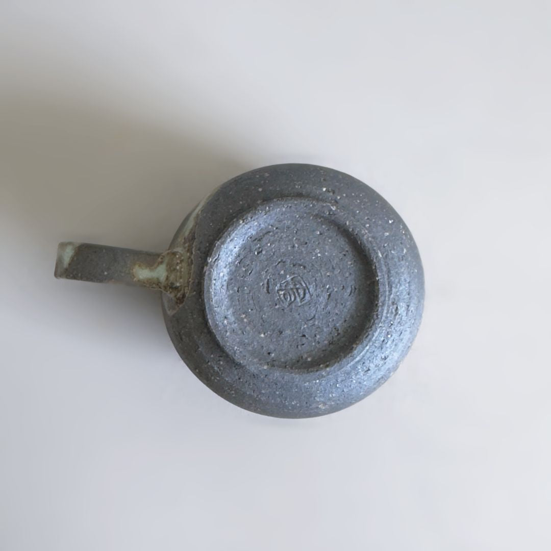 Underside of the Kisenyou mug showing the dark clay foot and maker’s stamp on a pale grey background.