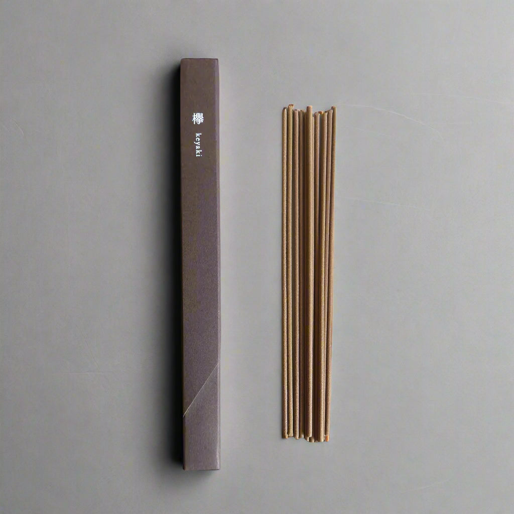 Top-down view of Kosaido Waboku Keyaki Zelkova Wood incense sticks next to minimalist brown box packaging.