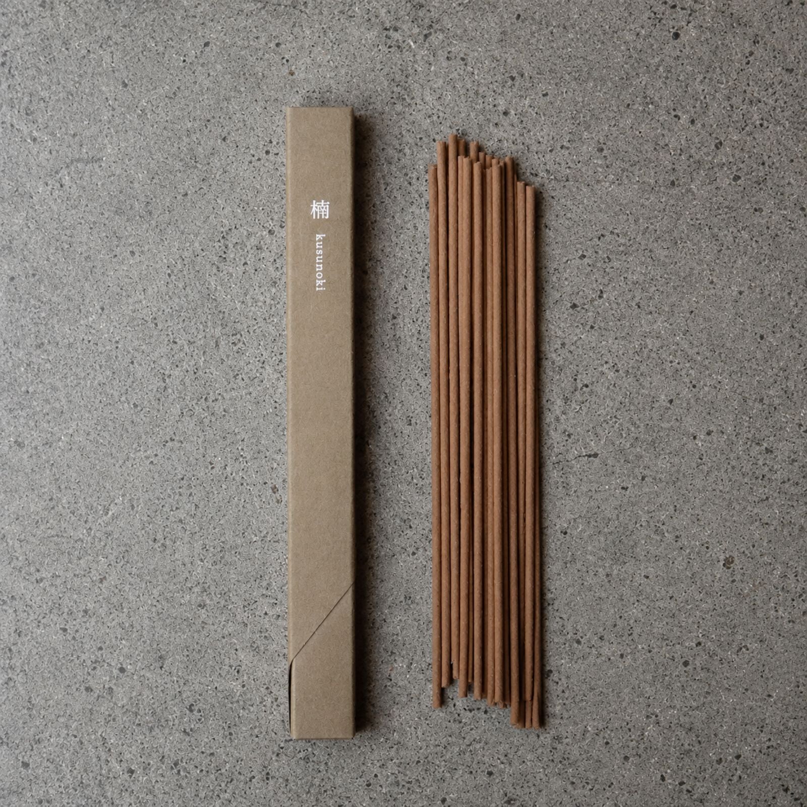 Top-down view of Kousaido Waboku Kusunoki(camphor) incense sticks next to minimalist olive green box packaging.