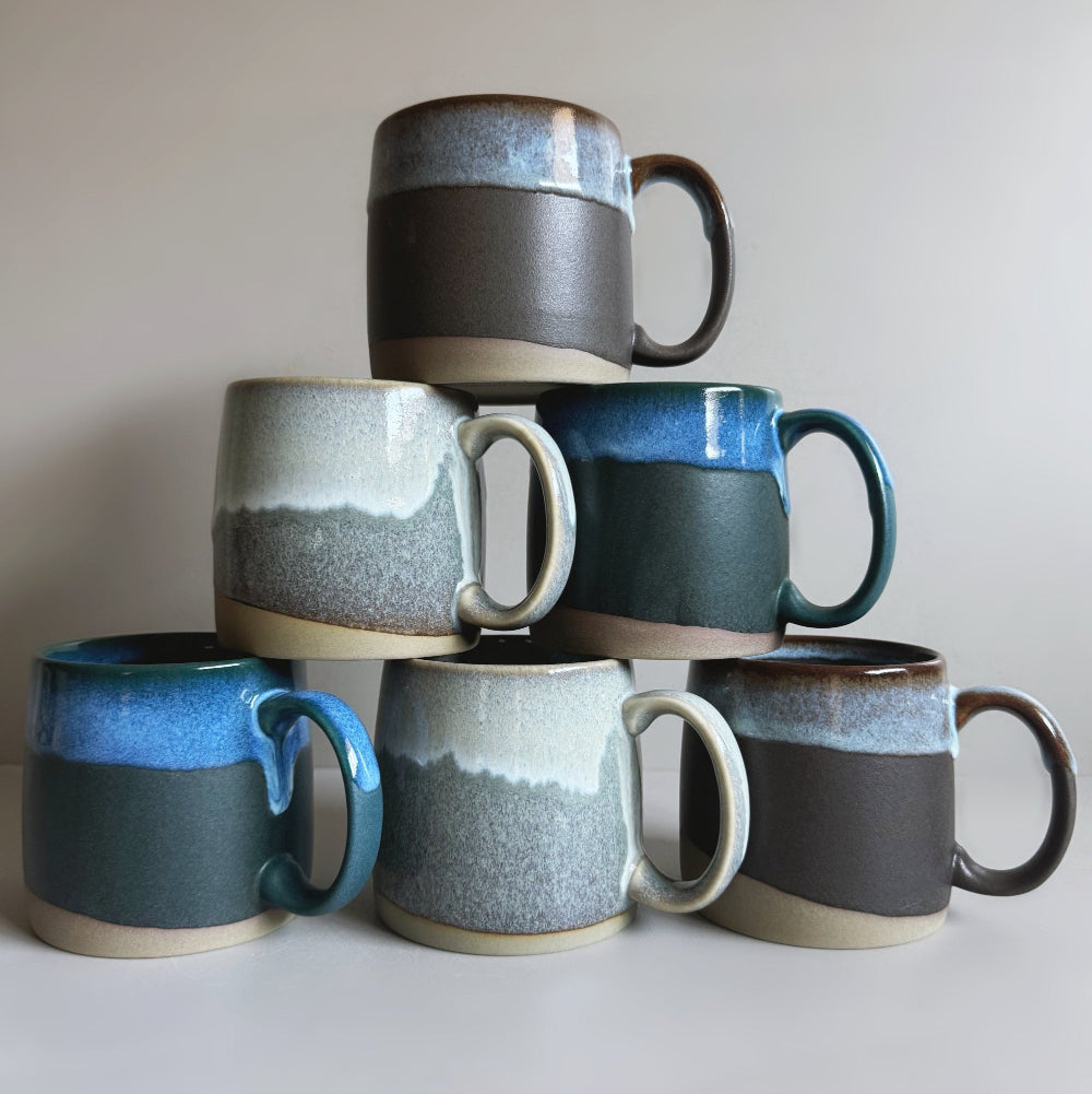 Stacked collection of TOKA Japanese ceramic mugs in multiple glazes, minimalist porcelain mug bundle.