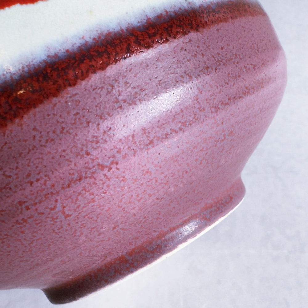 Close-up of a ceramic bowl with a speckled glaze on a white background