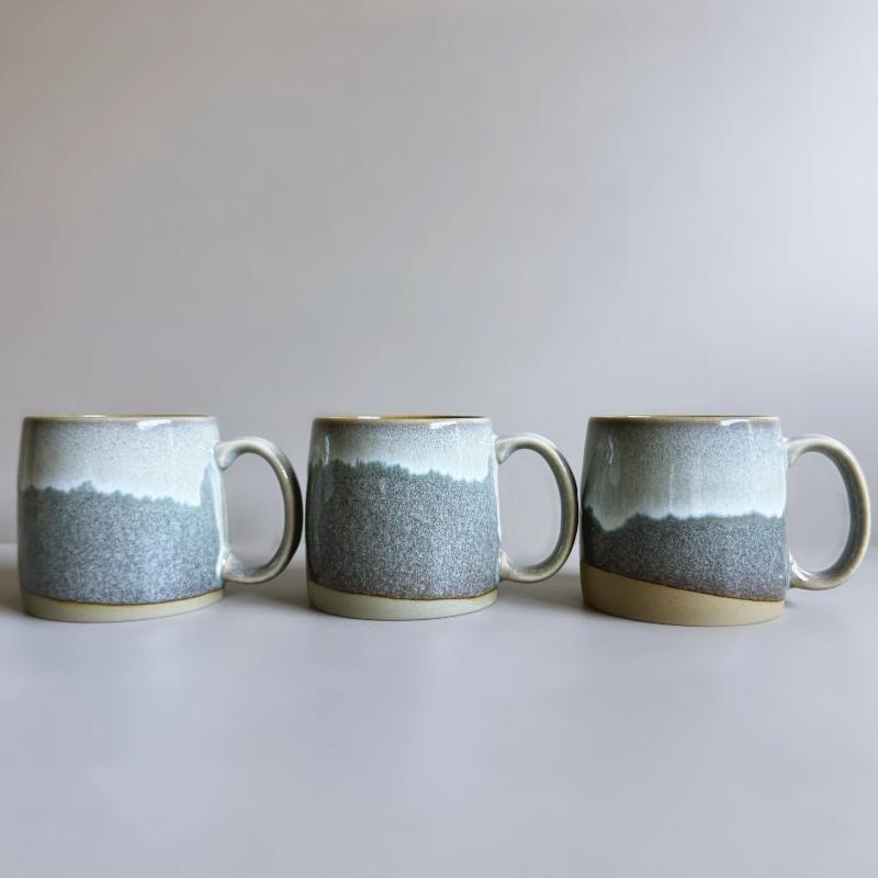 Three grey TOKA ceramic mugs lined up to show unique glaze variations, handmade Mino ware from Tajimi, Japan.