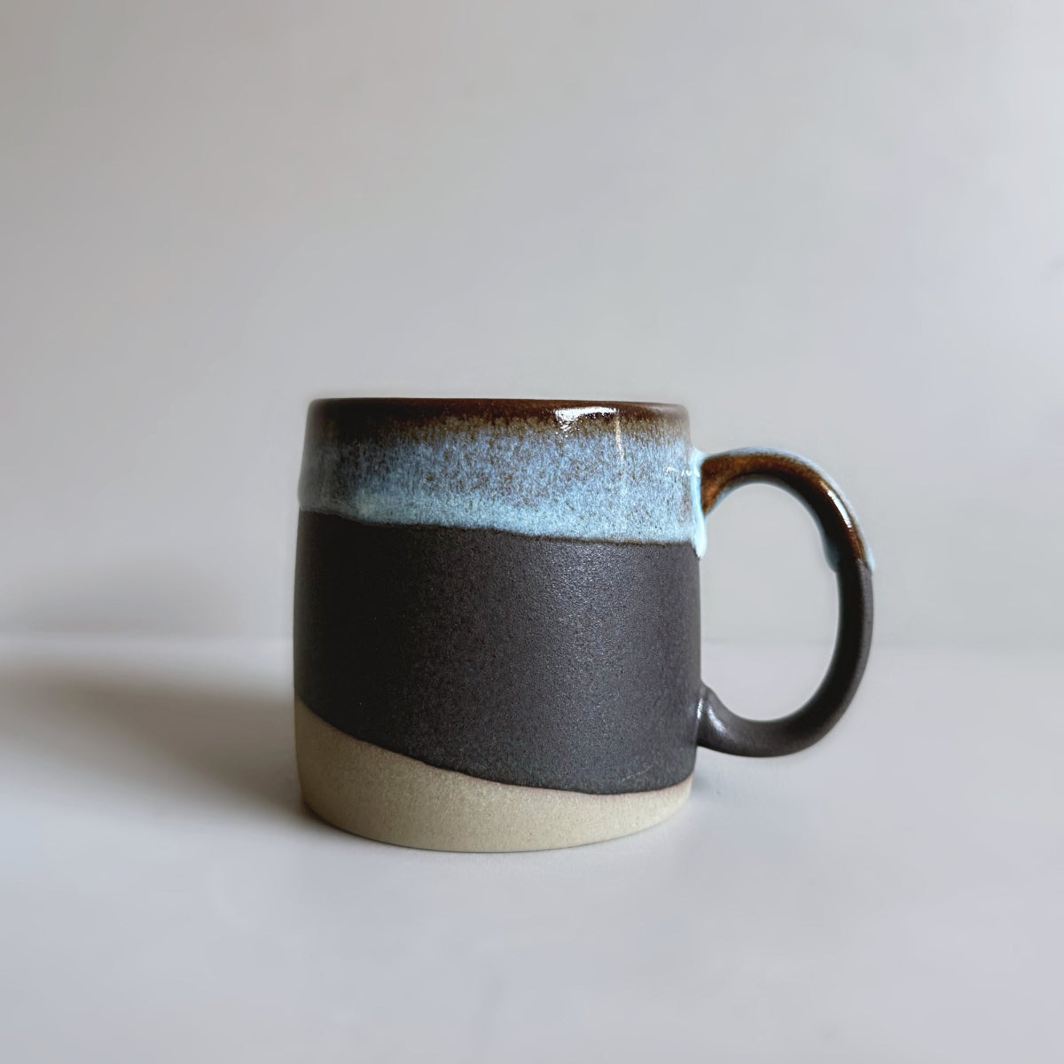 TOKA black ceramic mug with a dripping light blue and brown glaze rim, handmade Japanese Mino ware.