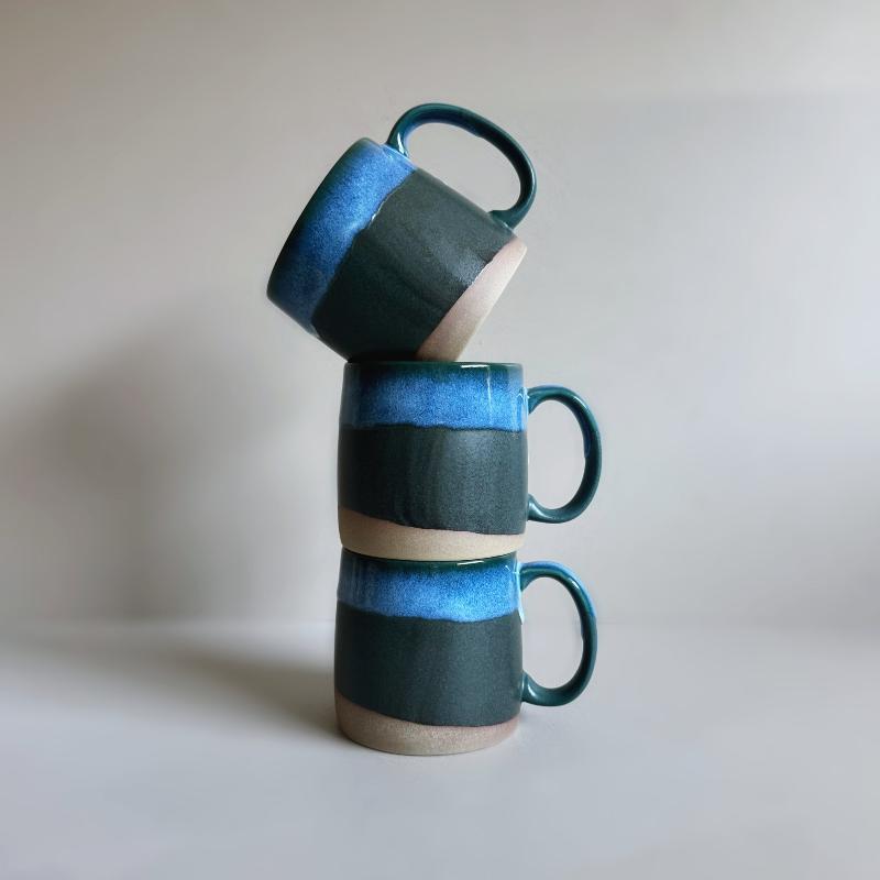 Vertical stack of three dark blue TOKA ceramic mugs with large handles, handmade Mino ware from Gifu, Japan.